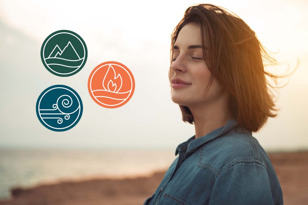 woman standing on a beach at sunset with three dosha icons representing vata, pitta, kapha